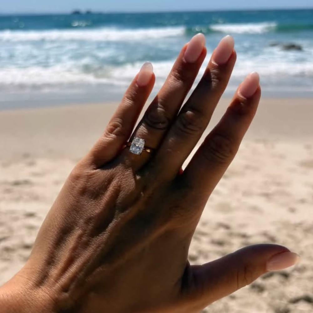 Sophie showing her elongated cushion-cut engagement ring by the sea