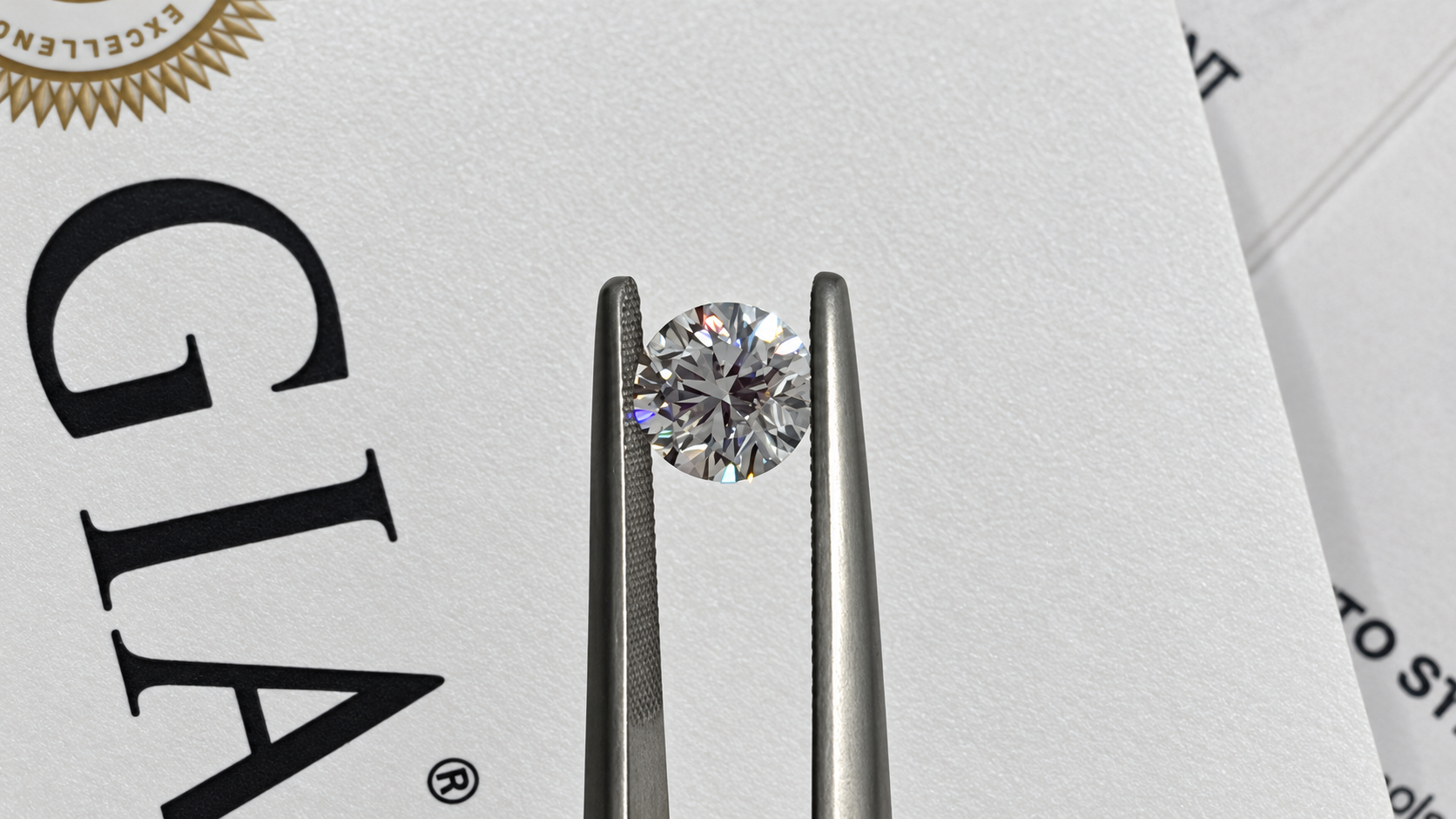 Loose round brilliant cut diamond held in tweezers over a GIA grading report